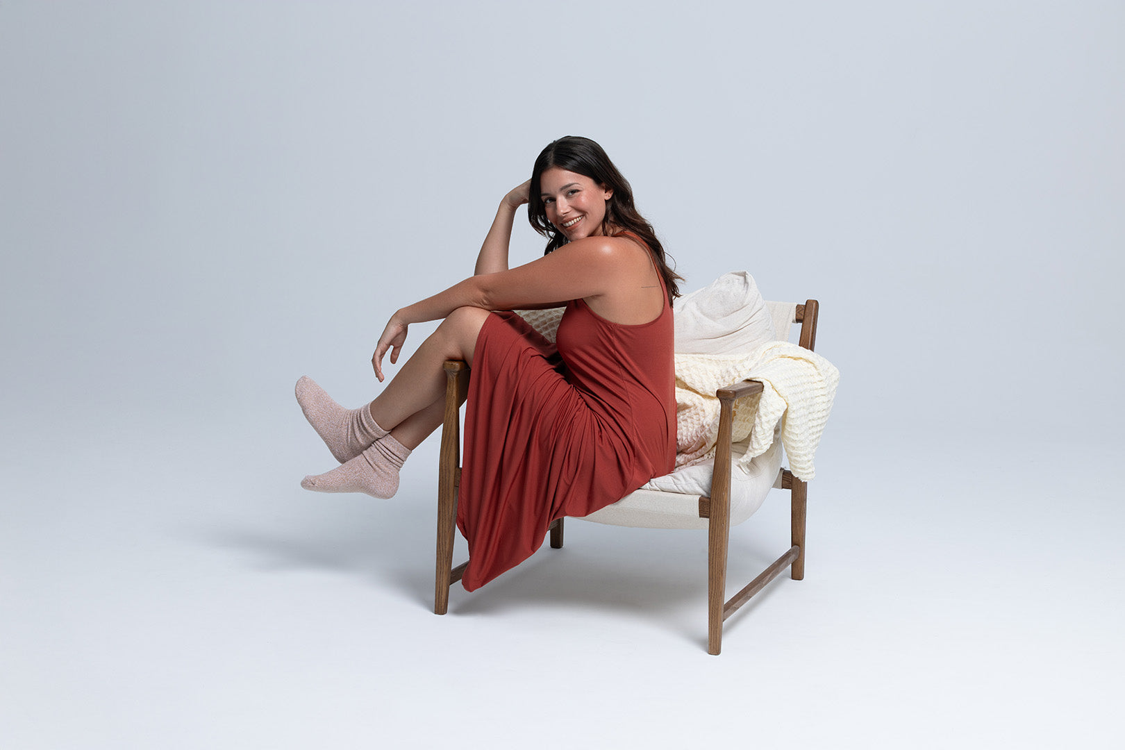 Woman sitting in chair wearing long racer back lounge dress for sleeping cool.